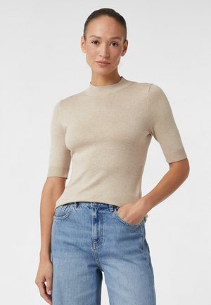 Beige Kurzarm-Strickoberteil mit rundem Halsausschnitt und gerippten Bündchen, kombiniert mit hellblauen, hoch taillierten Jeans.