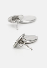 Brincos de metal com um design circular e liso. Acabamento em prata polida, fixados com um fecho de pino e detalhes em hardware redondo.