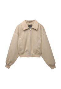 Beige faux suède kort jacka med en stor krage, frontdragkedja och två sidofickor. Har överdimensionerade ärmar och ribbade muddar.