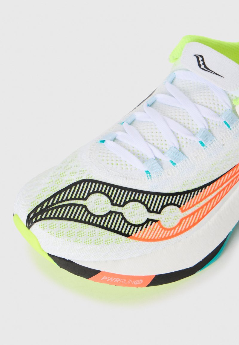 Baskets de course blanches avec doublure vert fluo, logo à motifs noirs et orange, lacets blancs et texte "PWRRUN PB" sur la semelle.