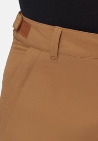 Bruine stoffen broek met een gladde textuur, voorzien van een platte tailleband, riemlussen en zichtbare stikseldetails.