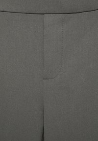 Grått tyg, slät textur, med en sidficka med en minimalistisk design och rena sömnadsdetaljer. Klassisk skräddarsydd passform.