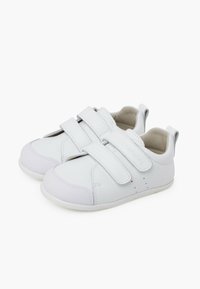Sneaker bianchi con strap in velcro, parte superiore in pelle liscia, suole in gomma, punta arrotondata e dettagli minimi, tra cui perforazioni sui lati.
