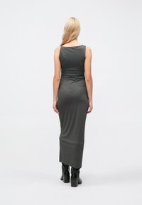 Pelēka pieguloša maksi kleita ar apaļu izgriezumu, ručkām vidukļa daļā un gludu faktūru, saskaņota ar melniem zābakiem ar biezu papēdi.