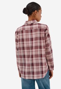 Košile s krátkým rukávem v pink, burgundy a krémové barvě. Má standardní límec, dlouhé rukávy a zakřivený spodní lem. Měkká textilní struktura.