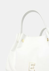 Borsa sintetica bianca con superficie texturizzata, dettagli in metallo dorato, manici superiori e una lettera "E" in evidenza sul davanti.