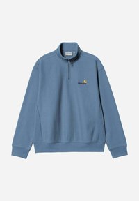 Sudadera de forro polar azul con cuello alto con cremallera, bolsillos laterales y logo bordado en amarillo y granate en el lado izquierdo del pecho. Textura suave.