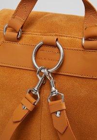 Bolso tote de ante naranja con detalles de cuero. Cuenta con herrajes plateados, asas dobles y correa de hombro desmontable con clips.