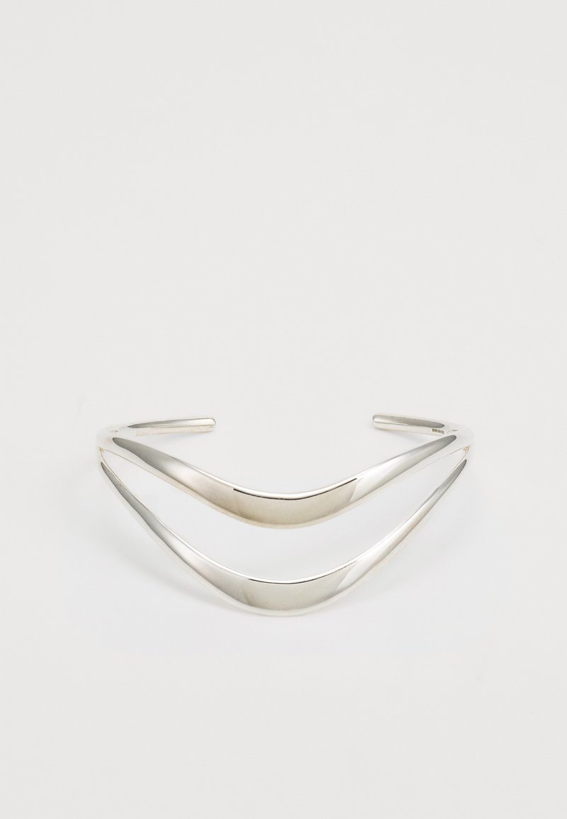 Ασημένια μεταλλική κορδέλα για τα μαλλιά με δύο καμπυλωτές, επικαλυπτόμενες γραμμές; λείος φινίρισμα, ανοιχτές άκρες, σύγχρονος σχεδιασμός.