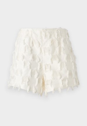 White shorts featuring a textured fabric with fringe accents and an intricate grid pattern. The design is high-waisted with a frayed finish.
