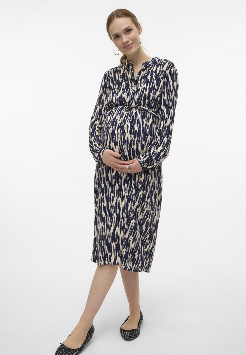 Långärmad amningsklänning med ett marinblått och elfenbensfärgat ikatmönster, insvängd i midjan, med en knappkrage och knälength.