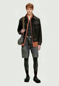 Jachetă din denim neagră, cămașă în carouri portocalii, pantaloni scurți gri și colanți cu model. Pantofi negri cu un finisaj texturat. Geantă de umăr gri.