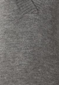 Suéter de punto gris con una textura suave, con un diseño acanalado en el cuello y cuerpo liso. Patrón de puntada uniforme en toda la prenda.