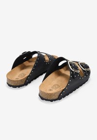 Sandalias negras de slip-on con plantilla de corcho, acentos de tachuelas doradas y correas de doble hebilla. Suela texturizada para mayor agarre y comodidad.