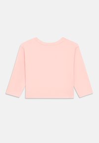 Jasnoróżowa koszula z długim rękawem, okrągłym dekoltem i krótkim krojem. Gładka faktura, minimalne detale szwów, bez widocznych ozdób.