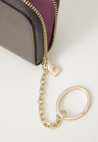 Portafoglio grigio e viola con zip e finiture dorate, dotato di un attacco a catena e anello portachiavi. Materiale texturizzato, forma rettangolare.