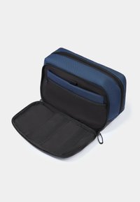 Borsa organizer in tessuto blu con chiusura a zip, presenta un interno nero con scomparti e cinturini elastici per mantenere gli oggetti al sicuro.