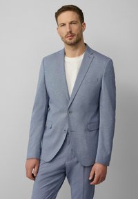 Helles blaues Sakko aus maßgeschneidertem Stoff mit strukturiertem Muster, zwei Knöpfen, Reverskragen und Vorderentaschen, kombiniert mit einem weißen Hemd.