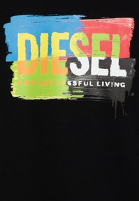 Camiseta negra con gráfico estilo pintura multicolor. El texto dice "DIESEL PARA UNA VIDA EXITOSA" en blanco y naranja.
