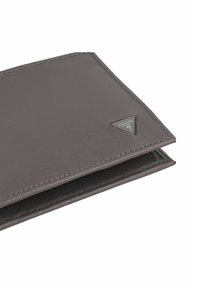 Portafoglio bi-fold grigio con superficie testurizzata e piccolo logo metallico triangolare sull'angolo, parzialmente aperto su sfondo bianco.