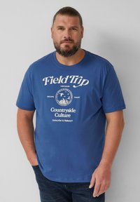 Niebieska koszulka z krótkim rękawem i okrągłym dekoltem, z białym tekstem graficznym i logo. Wykonana z miękkiej bawełny, na jednolitym tle.