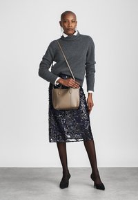 Siva pletena majica, navy barve krilo stilsko svinčnik s sequins, črne hlačne nogavice, črne čevlje z visoko peto in bež torbica čez telo s strukturiranim dizajnom.