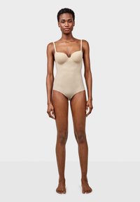 Bodysuit beige con copas acolchadas, tirantes finos y textura suave. Presenta un diseño ajustado que contorne la figura.