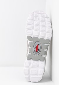 Sneaker-Sohle mit einer strukturierten weißen Gummiaußensohle, grauem Zwischensohlenelement und einem roten sowie silbernen Logo auf grauem Akzent. Das Obermaterial besteht aus hellgrauem Wildleder.