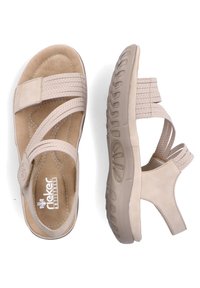 Sandalias beig con correas de tela entrelazadas, plantilla acolchada y suela de goma texturizada. Presentan una puntera redondeada y un cierre ajustable.