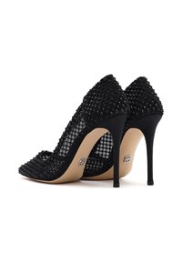 Des escarpins noirs avec un dessus en maille texturée recouvert de perles noires, un design à bout pointu et un talon aiguille. Semelle lisse de couleur nude.