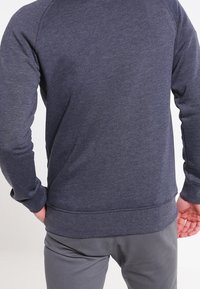 Tmavě šedá mikina s raglánovými rukávy, žebrovanými manžetami a lemem. Měkká textura, pohodlný střih, minimalistický design bez viditelných log.