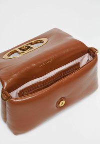 Sac à main en cuir marron avec une texture lisse, quincaillerie dorée et poche intérieure zippée. Présente un fermoir décoratif en or sur le dessus.