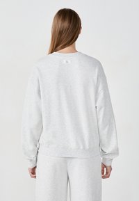 Grauer Pullover mit lässigem Schnitt, gerippten Bündchen und Saum. Mit einem kleinen Markenetikett am hinteren Ausschnitt. Weicher, strukturierten Stoff.