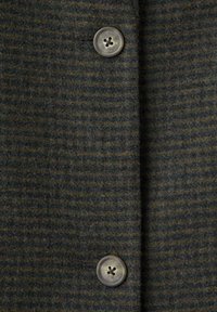 Dark gray and black striped wool fabric with two large gray four-hole buttons vertically aligned on a coat or jacket front.