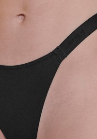 Zwarte stringonderbroek van zachte stof, met een delicate elastische band met logo-detail en een minimalistisch ontwerp.