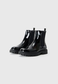 Botines Chelsea de charol negro con paneles laterales elásticos, puntera redonda y suela de goma gruesa con un diseño texturizado.
