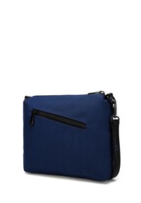 Krosbody taška z námořnického modrého textilu s přední zipovou kapsou a černým popruhem. Má hladký povrch a obdélníkový tvar.