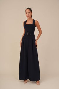 Námořnický overal s čtvercovým výstřihem, širokými ramínky, páskem v pase a širokými kalhotami s sklady. Hladká textura, minimalistické designové detaily.