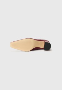 Tacco bordeaux con tomaia in pelle liscia, suola in gomma beige in contrasto e design a punta quadrata. Motivo a tasselli sulla suola.