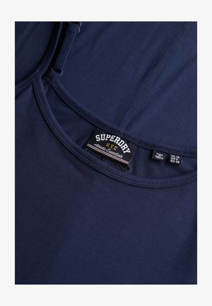 Granatowy dopasowany top bez rękawów wykonany z miękkiej bawełny. Posiada okrągły dekolt oraz metkę z napisem "Superdry Athletic Essentials".