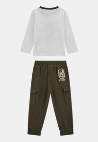 Haut à manches longues blanc avec col vert ; pantalon cargo vert olive avec logo et deux poches latérales ; tissu en coton ; coupe décontractée.