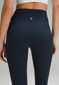 Högmidjade, sömlösa, mörk marinblå leggings tillverkade av elastiskt tyg med en liten logotyp mitt bak och en slät yta.