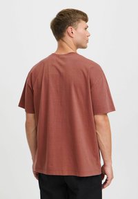 Rustfarvet bomulds T-shirt med afslappet pasform, korte ærmer og rund halsudskæring. Glat tekstur, minimale detaljer og lige kant.
