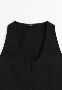 Veste noire sans manches avec trois boutons sur le devant et une étiquette indiquant Massimo Dutti à l'intérieur de l'encolure.