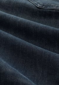 Tela de mezclilla azul oscuro con una textura suave, que presenta variaciones sutiles en la tonalidad y un clásico patrón de sarga.