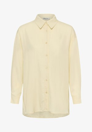 Hosszú ujjú, világos sárga, gombos ing hegyes gallérral és hét gombbal elöl, fehér háttéren, laposan kiterítve.
