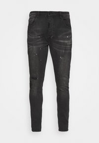 Vaqueros de mezclilla negra con un corte slim, que presentan detalles desgastados, salpicaduras de pintura, diseño de cinco bolsillos y pasadores para cinturón.