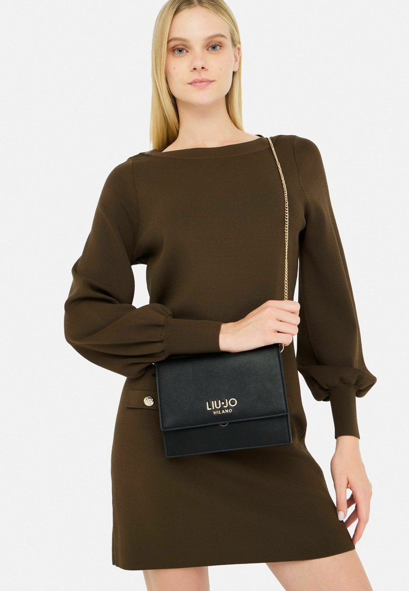 Borsa a spalla in pelle nera con hardware dorato, dotata di chiusura a pattina e del logo "LIU-JO MILANO" impresso sul davanti.