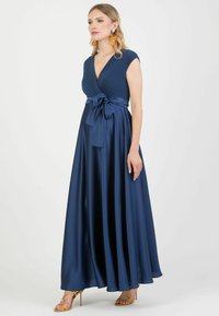 Abito lungo fino al pavimento di colore blu navy, realizzato in tessuto liscio, con scollo a V profondo, maniche a cappuccio e cintura in raso annodata in vita.