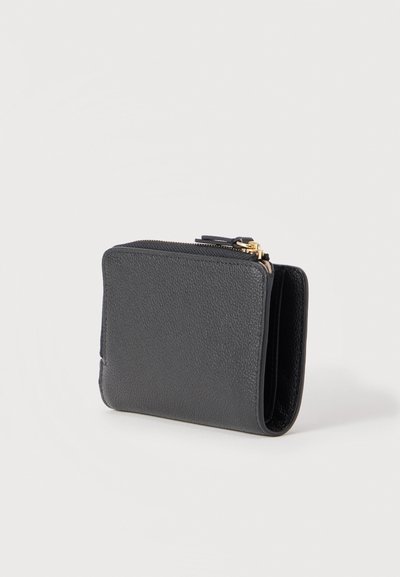 Μαύρο πορτοφόλι από υφή δέρματος με χρυσλό φερμουάρ, όρθιο σε λευκή επιφάνεια, μερικώς ανοιχτό που δείχνει τα εσωτερικά διαμερίσματα.